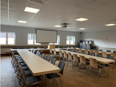 Saal mit Bestuhlung, Beamer und Leinwand